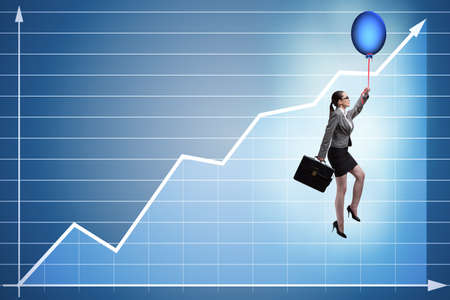 Businesswoman flying on hot balloon over graphの写真素材
