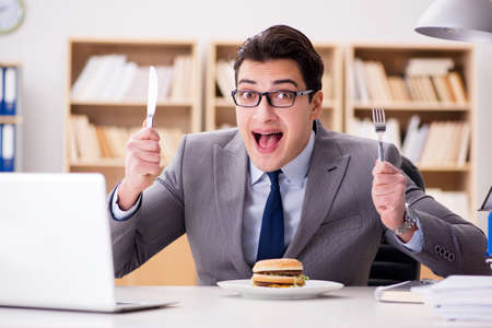 Hungry funny businessman eating junk food sandwichの写真素材
