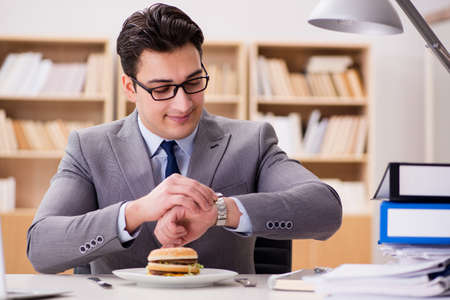Hungry funny businessman eating junk food sandwichの写真素材