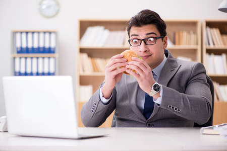 Hungry funny businessman eating junk food sandwichの写真素材