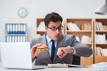 Hungry funny businessman eating junk food sandwichの写真素材