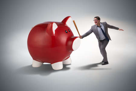 Angry man with baseball bat hitting piggybankの写真素材