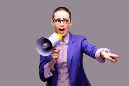 Young businesswoman with loudspeaker on gray backgroundの写真素材