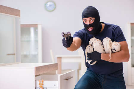 Robber wearing balaclava stealing valuable things