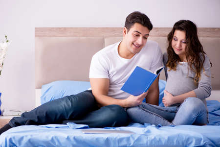 Young family with pregnant wife expecting baby in bedの写真素材