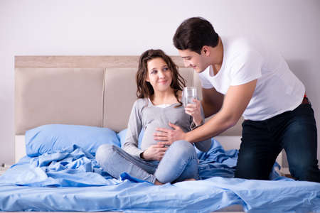 Young family with pregnant wife expecting baby in bed