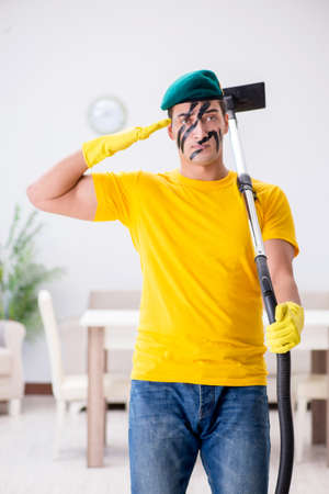 Funny man in military style cleaning the houseの写真素材