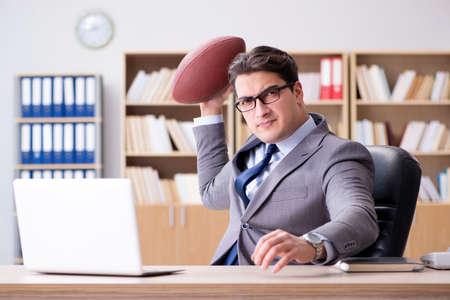 Businessman with american football in officeの写真素材