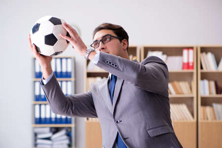 Businessman with football ball in officeの写真素材