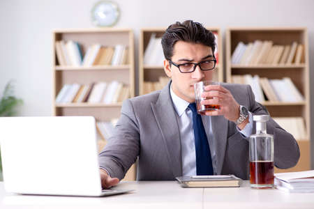 Young businessman drinking from stressの写真素材