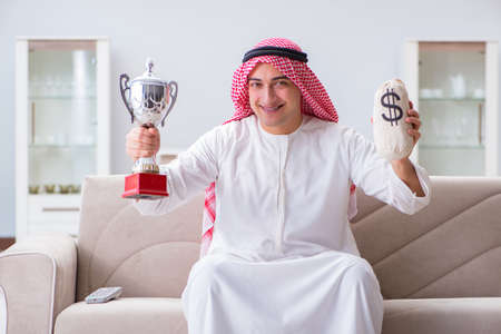 Arab man with prize and money on sofaの写真素材