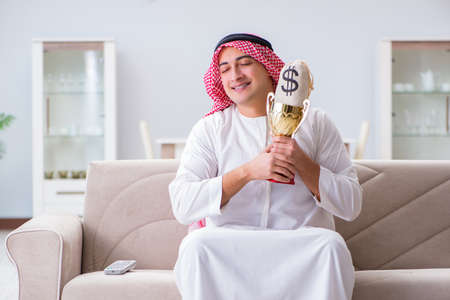 Arab man with prize and money on sofaの写真素材
