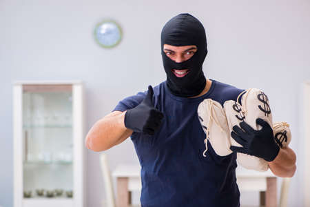 Robber wearing balaclava stealing valuable things