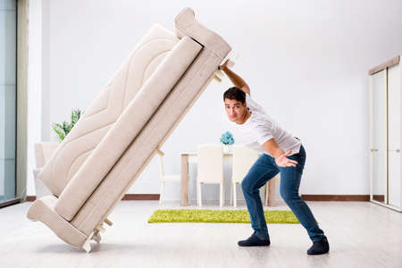 Young man moving furniture at homeの写真素材
