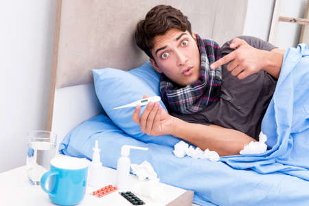 Sick ill man in the bed taking medicines and drugsの写真素材