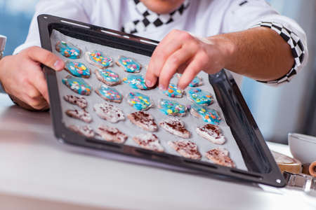 Young man cooking cookies in kitchenの写真素材