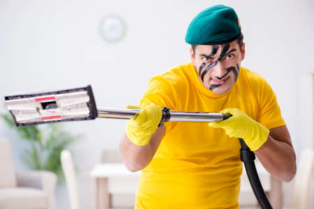 Funny man in military style cleaning the houseの写真素材