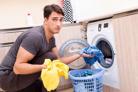 Young husband man doing laundry at homeの写真素材