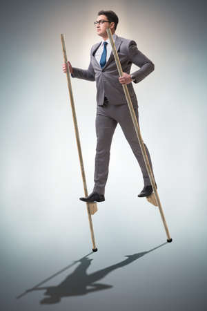 Businessman walking on stilts - standing out from the crowdの写真素材
