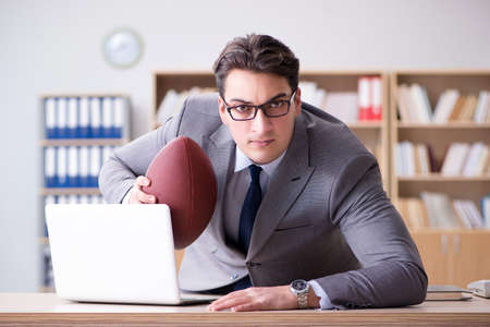 Businessman with american football in officeの写真素材