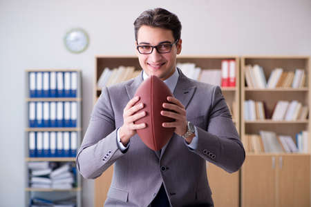 Businessman with american football in officeの写真素材