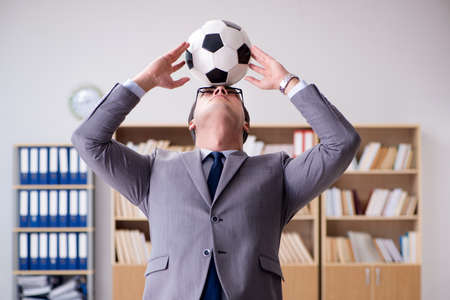 Businessman with football ball in officeの写真素材