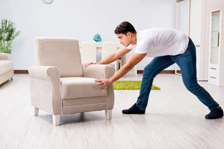 Young man moving furniture at homeの写真素材