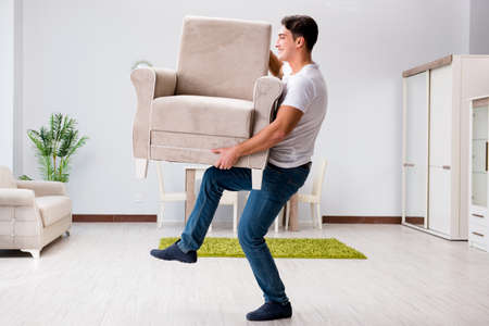 Young man moving furniture at homeの写真素材