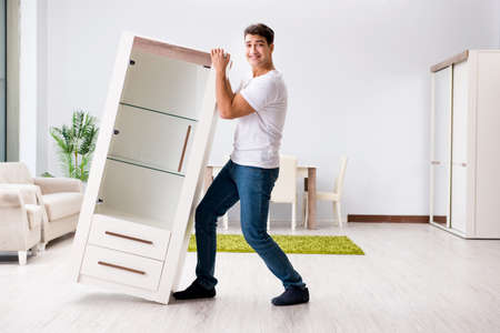 Young man moving furniture at homeの写真素材