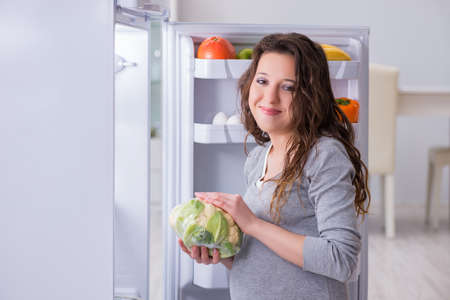 Pregnant woman near fridge looking for food and snacksの写真素材