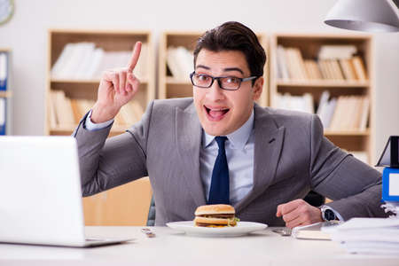 Hungry funny businessman eating junk food sandwichの写真素材