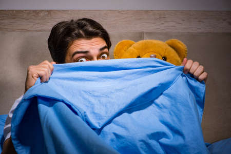 Young man scared in bedの写真素材