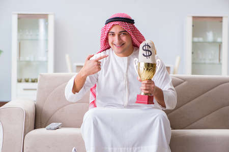 Arab man with prize and money on sofaの写真素材