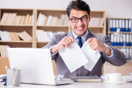 Angry businessman with too much work in officeの写真素材