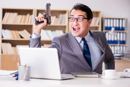 Funny businessman with gun in officeの写真素材