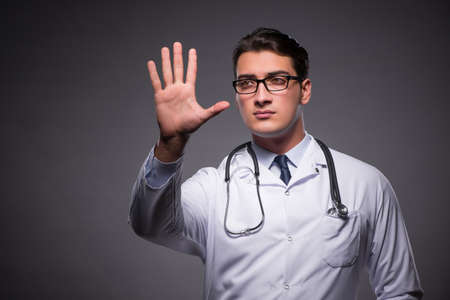 Young doctor against dark backgroundの写真素材