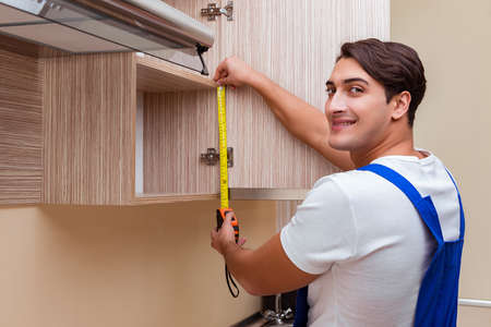 Young man assembling kitchen furnitureの写真素材