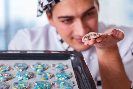 Young man cooking cookies in kitchenの写真素材