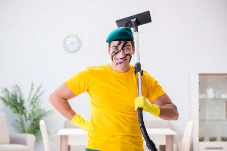 Funny man in military style cleaning the houseの写真素材