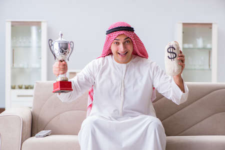 Arab man with prize and money on sofaの写真素材