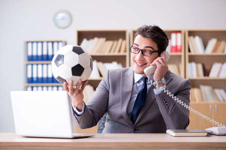 Businessman with football ball in officeの写真素材