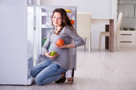 Pregnant woman near fridge looking for food and snacksの写真素材
