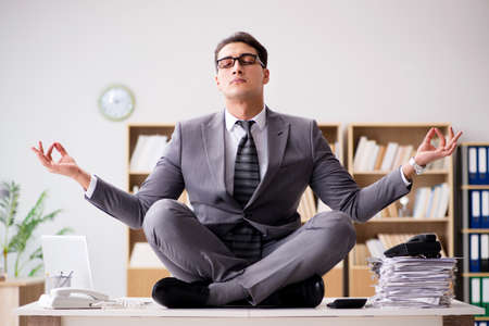 Young businessman meditating in the officeの写真素材
