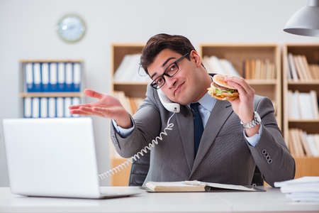 Hungry funny businessman eating junk food sandwichの写真素材