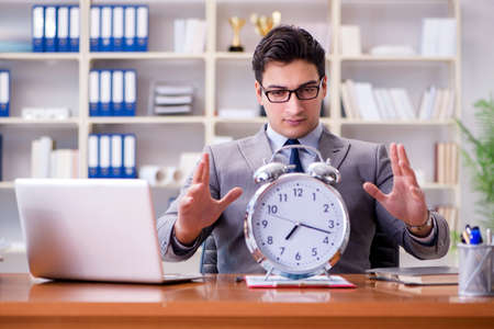 Young businessman in time management conceptの写真素材