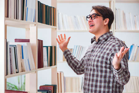 Young student looking for books in college libraryの写真素材