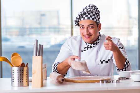 Young man cooking cookies in kitchenの写真素材