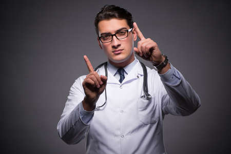 Young doctor against dark backgroundの写真素材