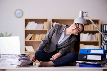 Busy angry businesswoman sitting on the desk in officeの写真素材