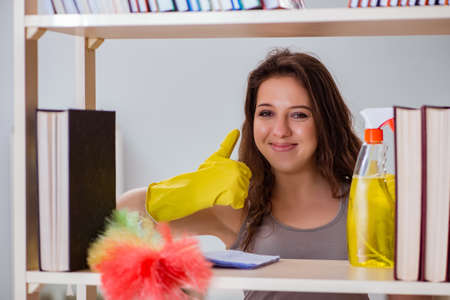 Woman cleaning dust from bookshelfの写真素材